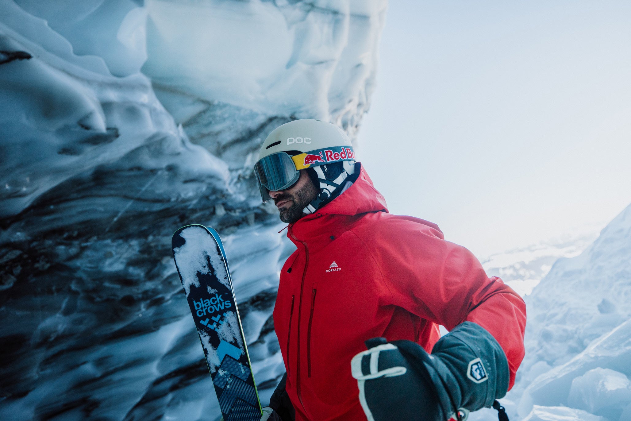 Skier in a red Cortazu hardshell jacket at the edge of a glacier ice cave
